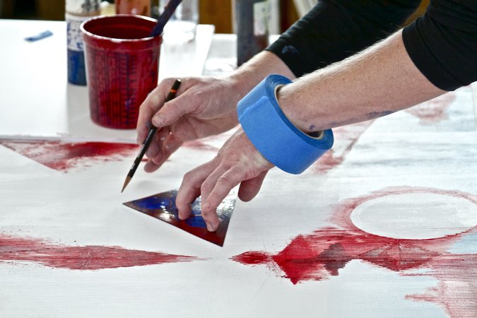 hands with blue tape red painting