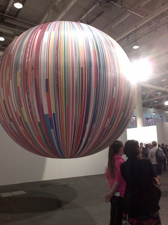 Resembling a planet orbiting around a star, Meschac Gaba's Citoyen du Monde: balloon (2013) partly eclipses one of the exhibition center's industrial lights.