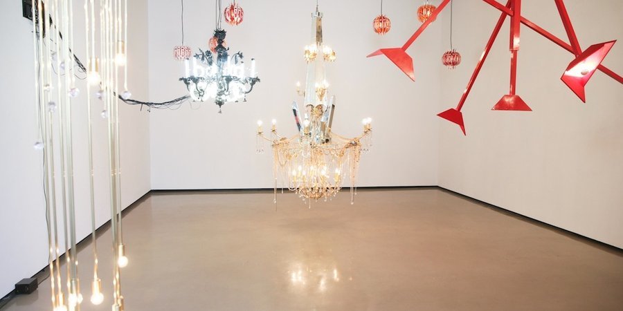 At Paul Kasmin, a brass-and-cut-lead crystal light fixture by Josiah McElheny (left) intermingle with Yuichi Higashionna's Venetian glass chandelier (left) and Jorge Pardo's steel garlands (back). At center hangs Dzine's custom chandelier 'Around the Way Girl,' and at right, Courtney Smith's 'Immobile (from the series Insatiable Spaces).' 