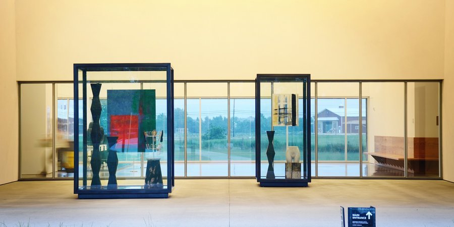 LEFT: "Tradition," 2013, cast concrete, chrome fixture, shoes, painted wood, acrylic on denim, and pigment print on anodized aluminum in blackened stainless steel and glass vitrine. RIGHT: 'Bright Bay Cars/Gratis,' 2013, cast concrete, painted wood, acrylic on canvas, pigment print on anodized aluminum in blackened stainless steel and glass vitrine.