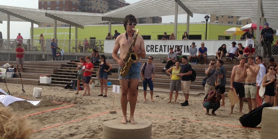 A saxophone playor performs at Jamie Isenstein's winning sand sculpture.